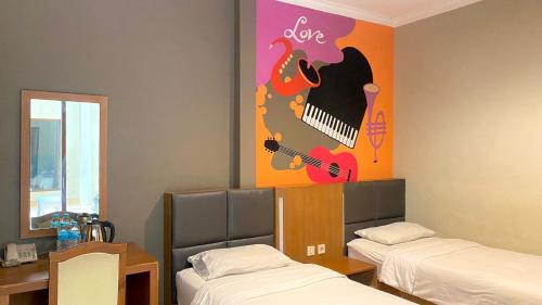 a room with two beds and a painting of a guitar at Votel Viure Hotel Jogjakarta in Yogyakarta