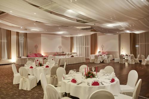 a banquet hall with white tables and white chairs at H4 Hotel Hamburg Bergedorf in Hamburg