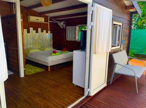 Cette chambre comprend un lit et une chaise sur une terrasse couverte. dans l'établissement Bungalow Ti Kako, à Capesterre-Belle-Eau