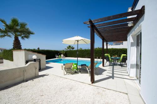 une terrasse avec une table, des chaises et une piscine dans l'établissement Sandy Coast Villas Anemone, à Argaka