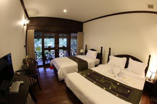 a hotel room with two beds and a television at Phubachiang Golf and Resort Pakse in Pakse