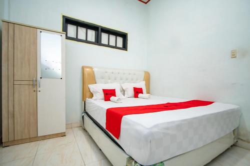 a bedroom with a white bed with a red blanket at RedDoorz Syariah near Danau Lut Tawar Takengon in Takengon