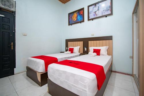 a bedroom with two beds with red and white sheets at RedDoorz Syariah near Danau Lut Tawar Takengon in Takengon