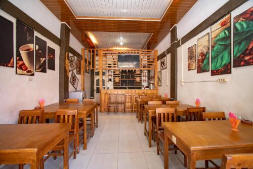 comedor con mesas y sillas de madera en RedDoorz Syariah near Danau Lut Tawar Takengon, en Takengon