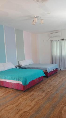 2 Betten in einem Zimmer mit Holzböden in der Unterkunft Wjv Inn Sta. Fe Bantayan in Ocoy