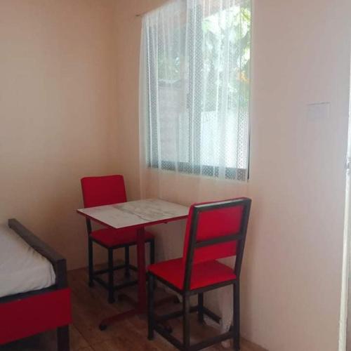 Zimmer mit einem Tisch, 2 Stühlen und einem Fenster in der Unterkunft Wjv Inn Sta. Fe Bantayan in Ocoy