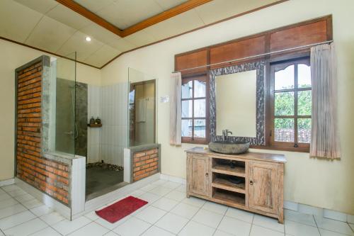 uma casa de banho com um chuveiro, um lavatório e um espelho. em KUDESA Homestay by Pramana Villas em Ubud