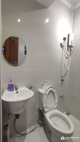 a bathroom with a toilet and a sink and a mirror at El Castillo Bed and Breakfast in Angono