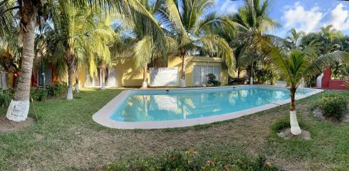 a swimming pool in front of a house with palm trees at CASA HUELLAS EN LA ARENA in Ixtapa