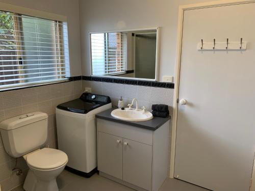 een badkamer met een toilet, een wastafel en een spiegel bij Ocean View in Port Macquarie