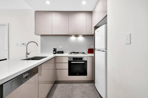 a white kitchen with a stove and a refrigerator at Stunning Corporate Apartment WAT1011601 in Sydney