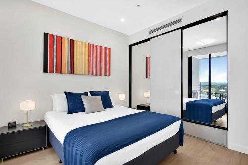 a bedroom with a blue and white bed and a balcony at Stunning Corporate Apartment WAT1011601 in Sydney