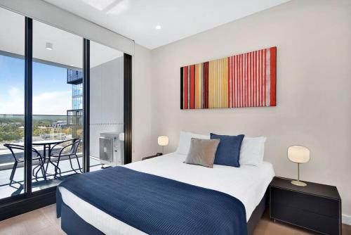 a bedroom with a bed and a balcony with a table at Stunning Corporate Apartment WAT1011601 in Sydney