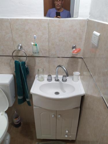 ein Badezimmer mit einem Waschbecken und einer Person im Spiegel in der Unterkunft Felicata in Sarmiento