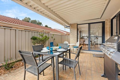 a patio with a table and chairs and a kitchen at Coastal Villa by Experience Jervis Bay in Vincentia