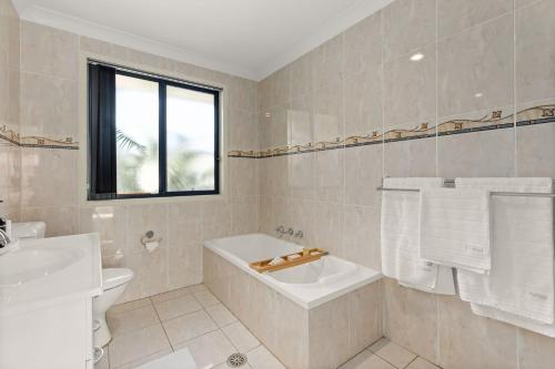 a bathroom with a tub and a toilet and a sink at Coastal Villa by Experience Jervis Bay in Vincentia