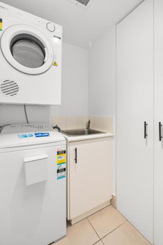 a laundry room with a sink and a washing machine at Oceanfront Penthouse Apartment Beach Club Palm Cove in Palm Cove
