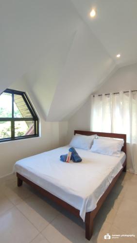 a bedroom with a large bed with white sheets and a window at El Castillo Bed and Breakfast in Angono