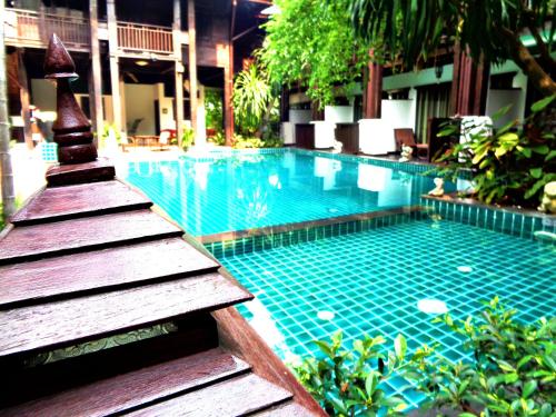 a swimming pool with a staircase leading to a building at Yantarasri Resort in Chiang Mai