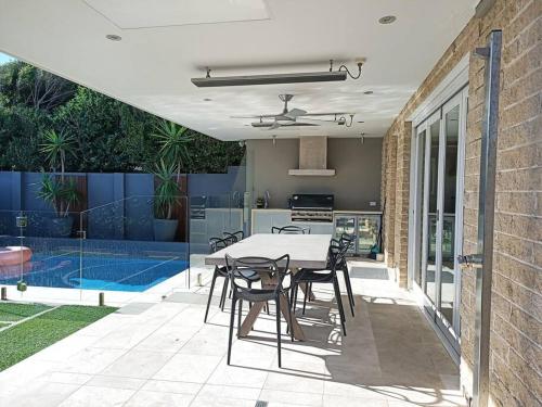 a patio with a table and chairs and a kitchen at Clovelly Beach House with Pool in Sydney