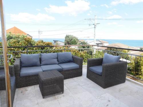 um pátio com 2 cadeiras e um sofá na varanda em Clovelly Beach House with Pool em Sydney