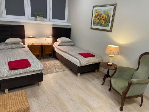 a room with two beds and a chair and a table at Przytulne w Centrum in Ostrowiec Świętokrzyski