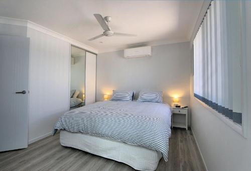a bedroom with a bed and a ceiling fan at Tanner St Retreat in Bargara