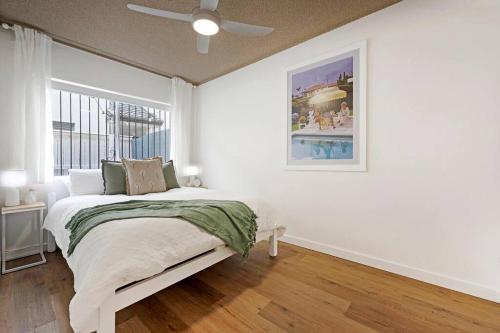 a white bedroom with a bed and a window at PALMA - Couples Beach Shack! in Gold Coast