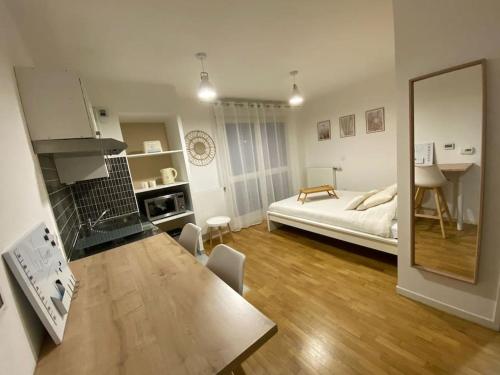 a kitchen and living room with a bed and a table at Studio Cosy à 10 min de Paris in Deuil-la-Barre