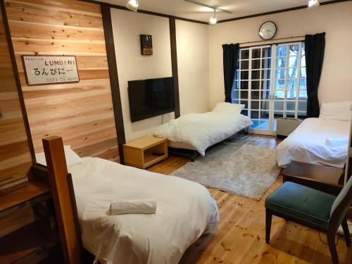 a room with two beds and a flat screen tv at Hakuba Matata Apartment in Hakuba