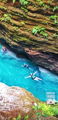 two people swimming in a pool of water next to a cave at House of TamSe Laagans ' Inn in Badian