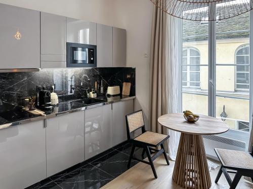 une cuisine avec des armoires blanches et une table avec des chaises dans l'établissement Canettes Deluxe Apartment, à Paris