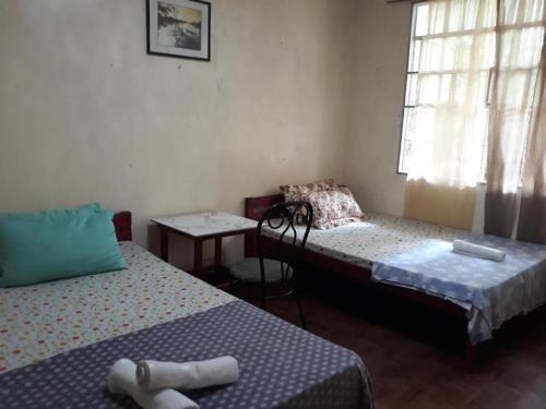 Cette chambre comprend 2 lits, une table et une fenêtre. dans l'établissement CVNB guesthouse, à San Juan