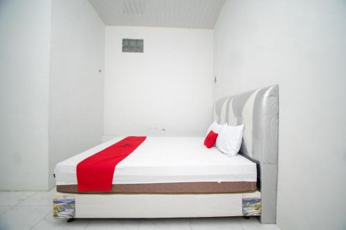 a white bedroom with a bed with a red blanket at RedDoorz Syariah near Danau Lut Tawar Takengon 2 in Takengon
