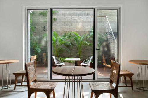 a room with a table and chairs and a large window at Bungalow 157 in New Delhi