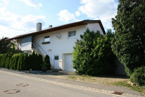 a white house with a garage next to a street at Liebevolle Fewo im Bayerischen Wald in Witzmannsberg