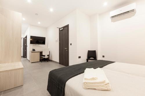 a white bedroom with a bed and a desk at No.48 Apartments in Msida
