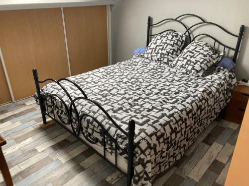 a bed with a black and white comforter and two pillows at Chambre meublée dans une maison in Vernouillet