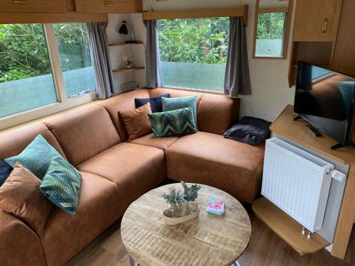 uma sala de estar com um sofá castanho e uma mesa em Vakantiepark de zanderij em Voorthuizen