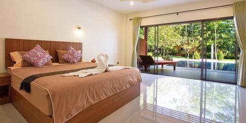 a bedroom with a bed and a large window at Baan Suan Villas Resort in Ban Suan
