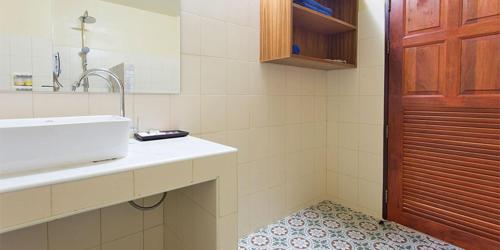 a bathroom with a sink and a mirror and a door at Baan Suan Villas Resort in Ban Suan
