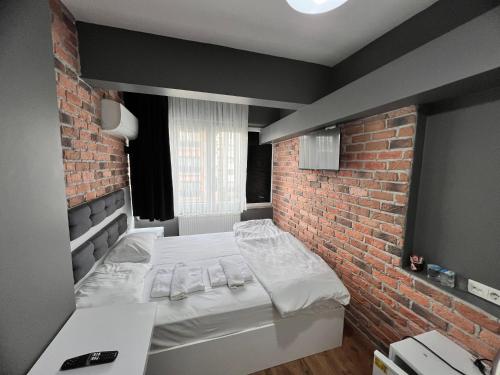 a bed in a room with a brick wall at Karaca Suite in Tuzla