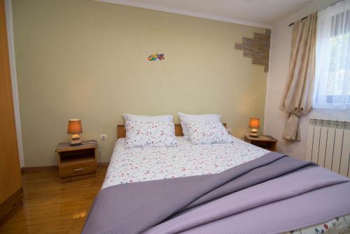 a bedroom with a large bed with two lamps on tables at Bato A2+1 in Veli Lošinj