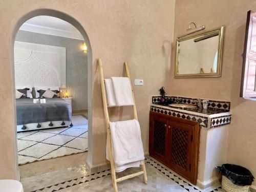 baño con lavabo, espejo y cama en Riad Jolie en Marrakech