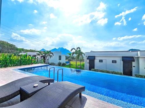 a swimming pool with chairs next to a house at Belong Jin The Dam Hotel And Resort in Ban Pha Saeng Lang