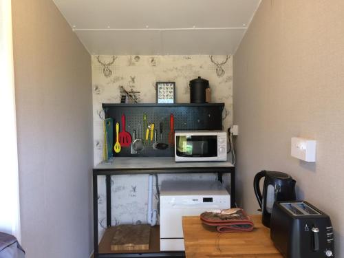 a small kitchen with a microwave and a table at Woodman's Rest in Kirdford