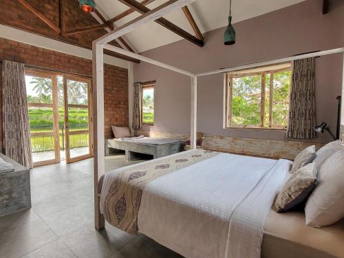 a bedroom with a bed in a room with windows at Les Rizieres Lombok - Tetebatu in Tetebatu