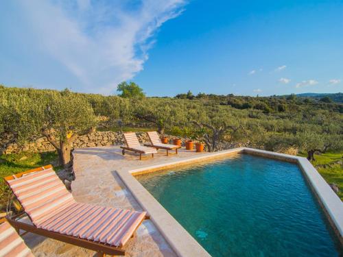 a swimming pool with two lounge chairs next to at Villa Roza in Splitska