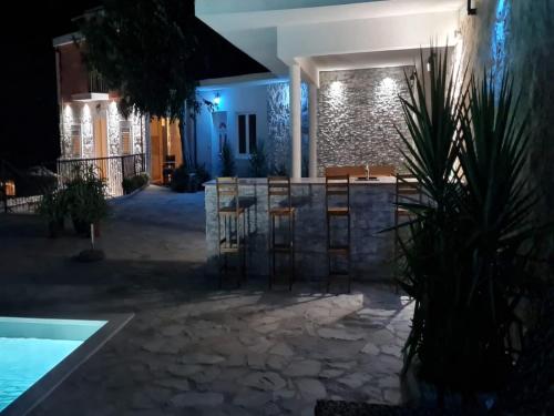a patio with a bar and a pool at night at Holiday Home Mico in Drvenik