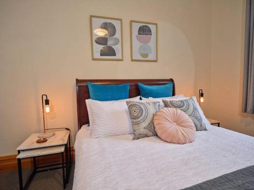 ein Schlafzimmer mit einem weißen Bett mit Kissen in der Unterkunft Beautiful Cottage in cosmopolitan Norwood in Kensington and Norwood